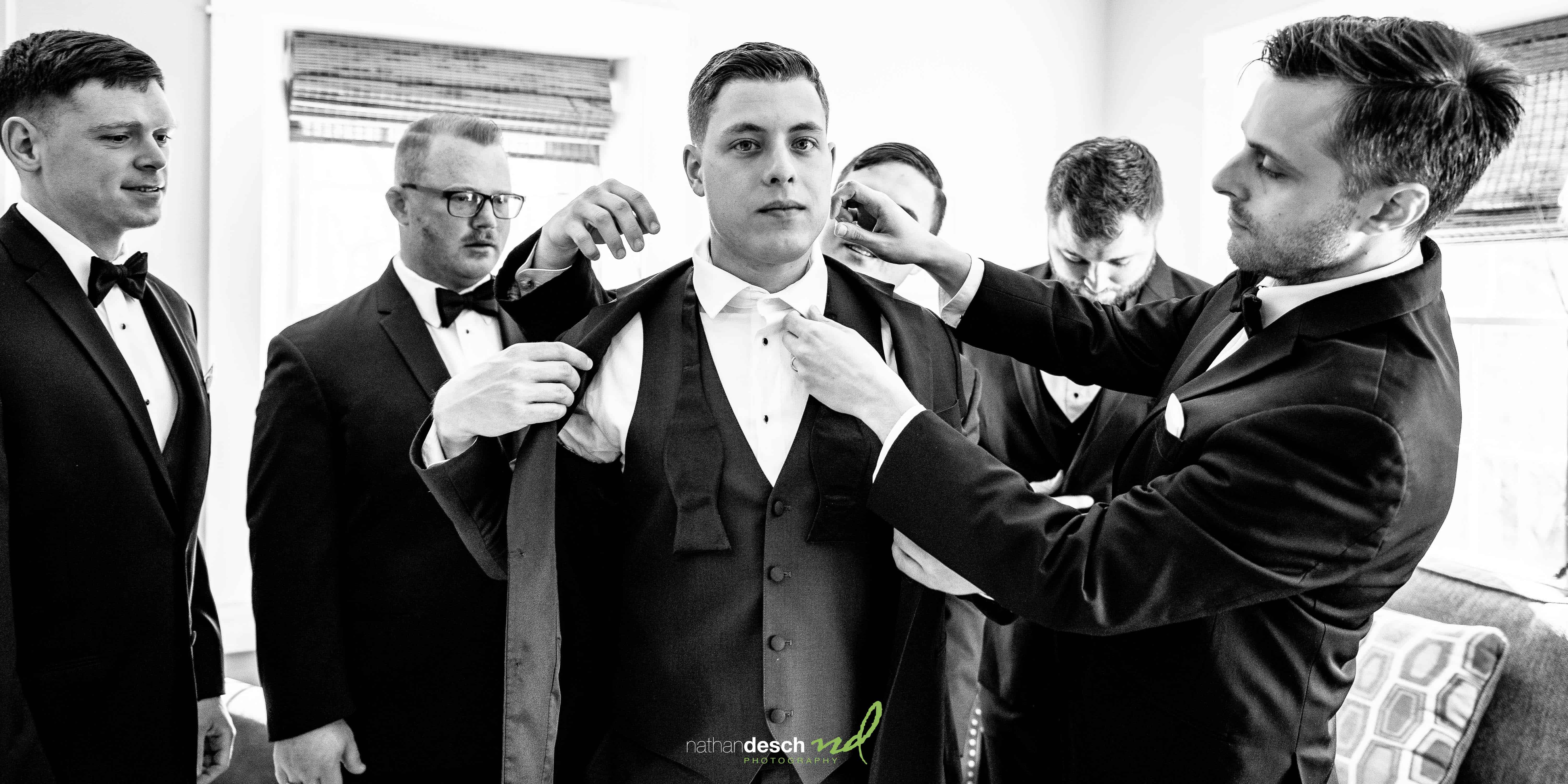 guys helping groom get dressed