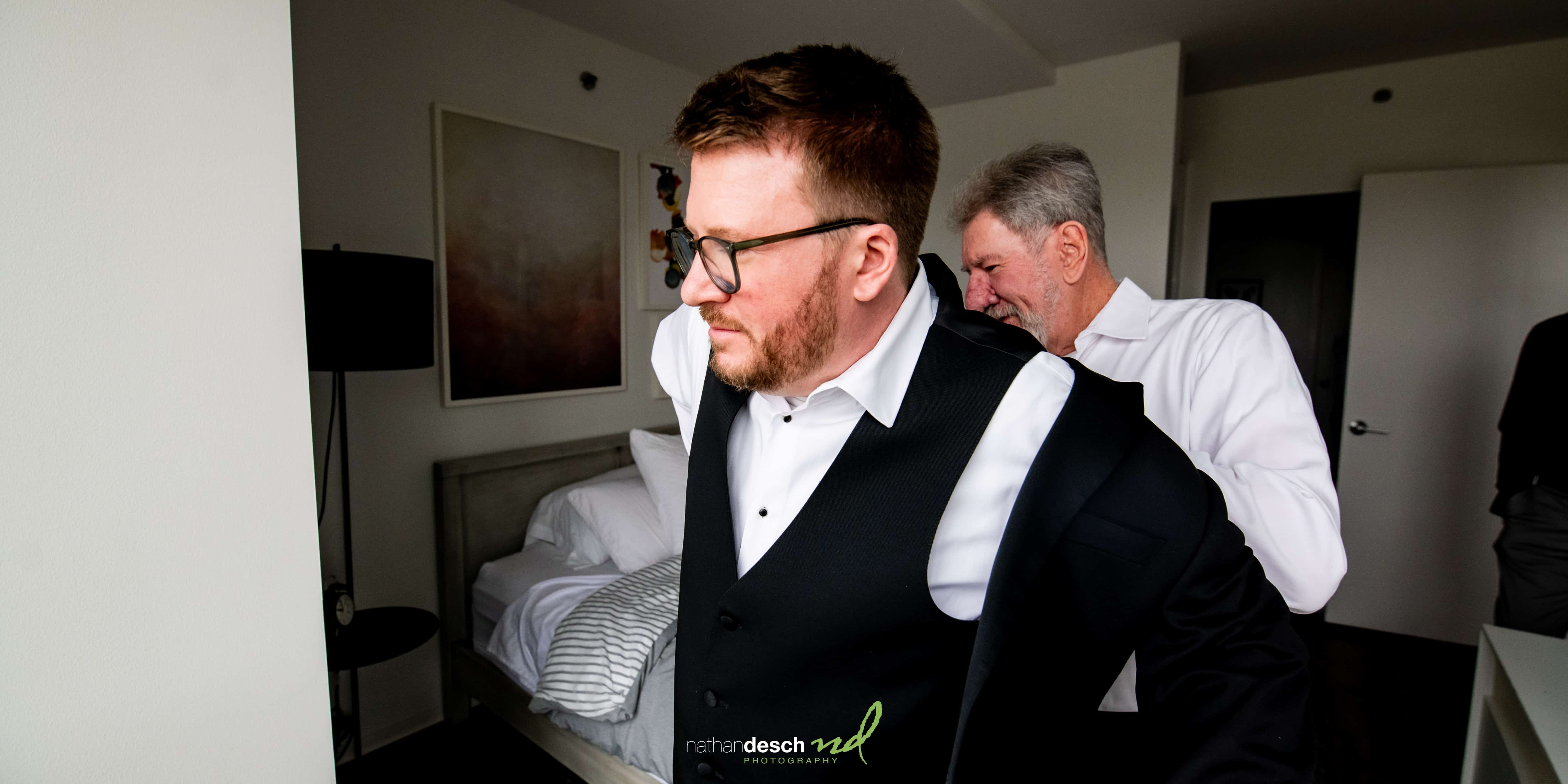 father helping groom get dressed