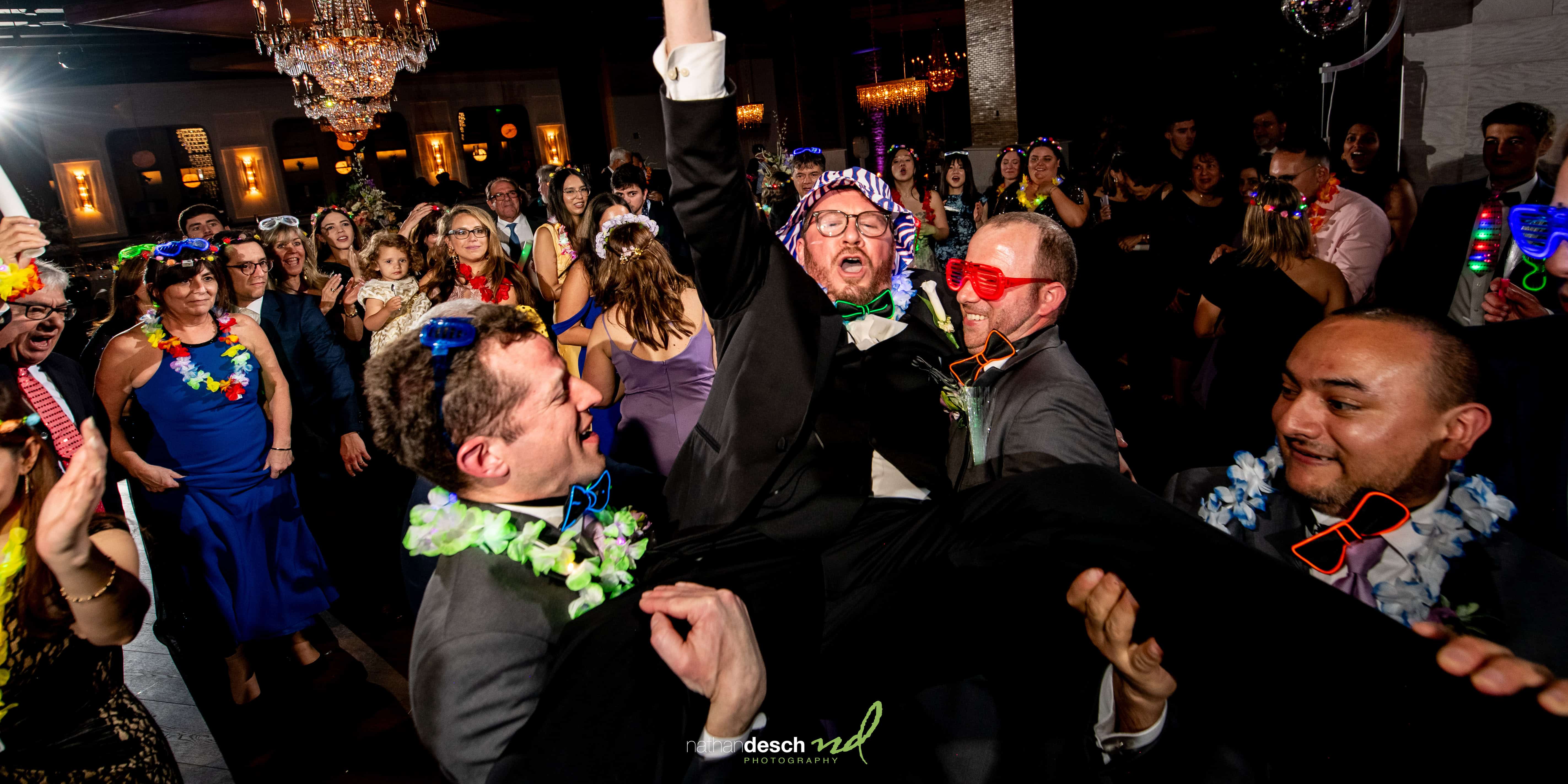 guys lifting groom at reception