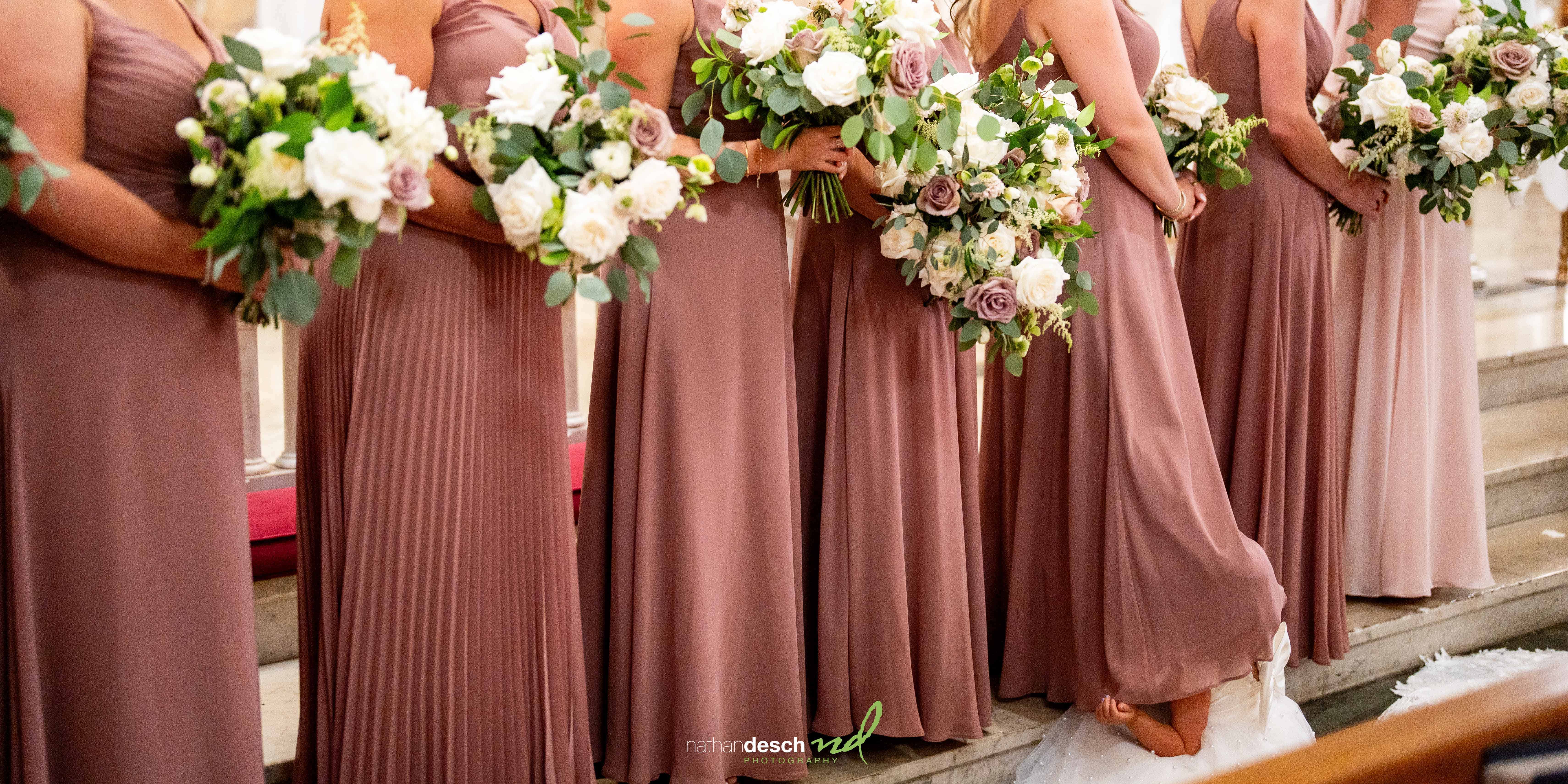 Flower girl hiding under bridesmaid's dress